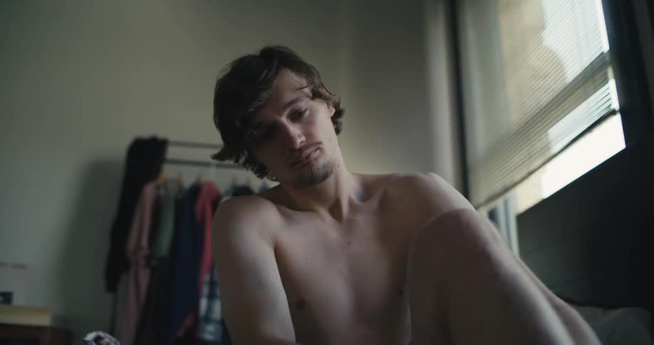 Man sits on side of bed to put on his prosthetic and get dressed before standing
