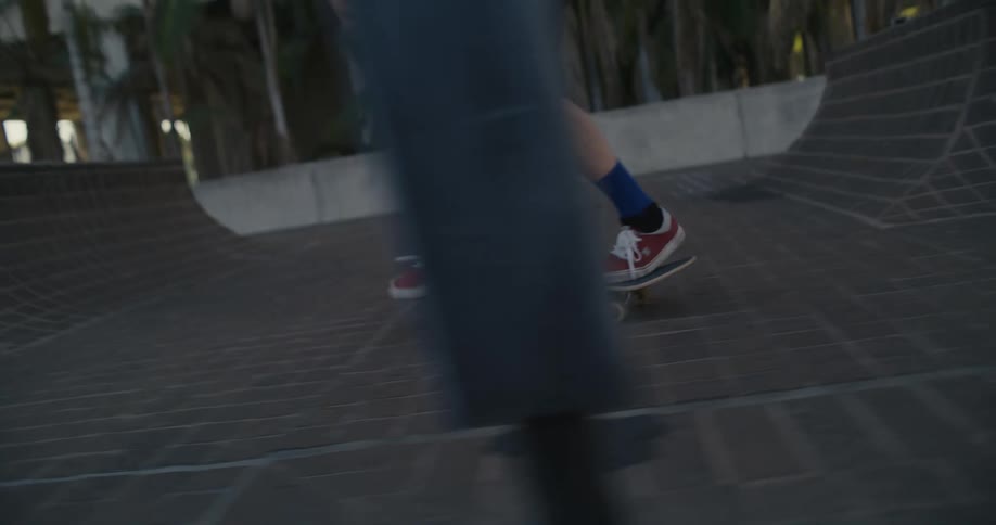 Man with leg prosthetic trips and falls of skateboard near steps