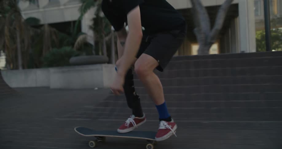 Skateboarder wearing a prosthetic brace tries to spin skateboard and falls off board