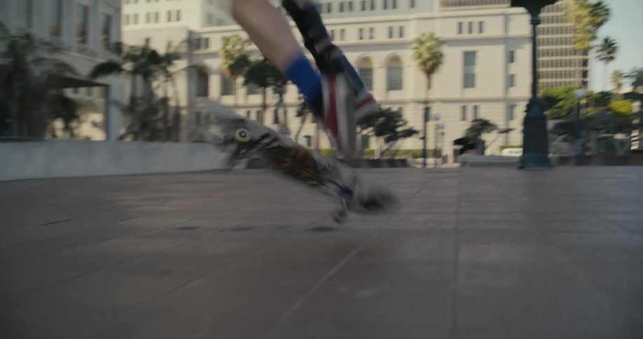 A teenager attempts a kick flip stunt on a skateboard but fails to land back on the board