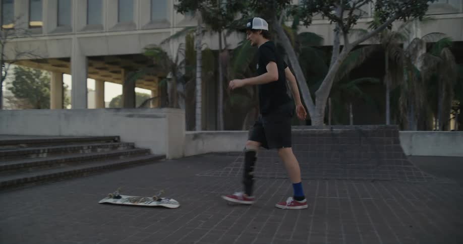 A skateboarder with a leg brace jumps down steps on his skateboard