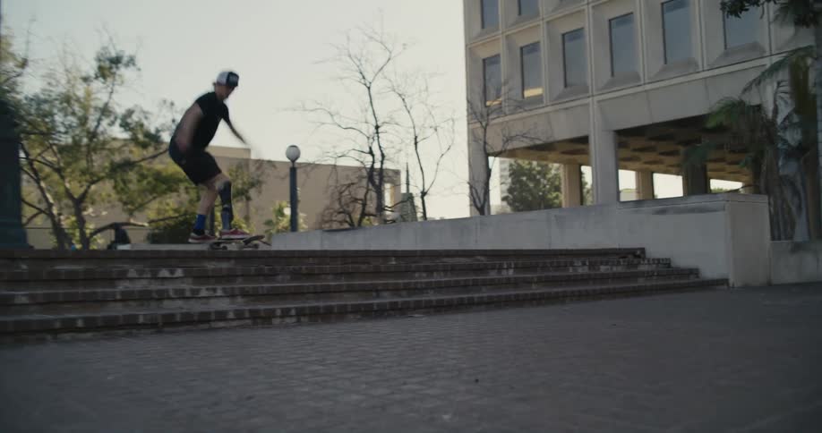 Skateboarding male wearing leg brace takes jump over steps