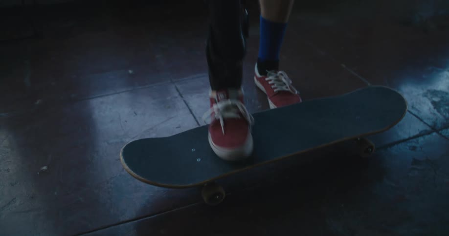 A man with an artificial leg flips a skateboard in the air and puts it on the floor and stands on it