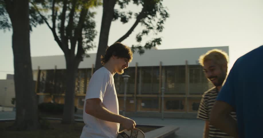 A group of guys fist bump in a skate park and holding a skateboard