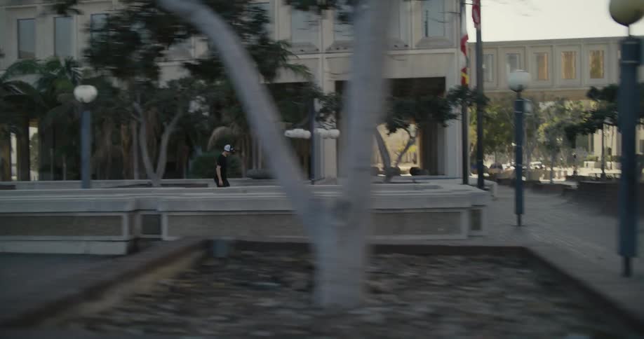 A person skateboards across a town concourse towards a sidewalk and road