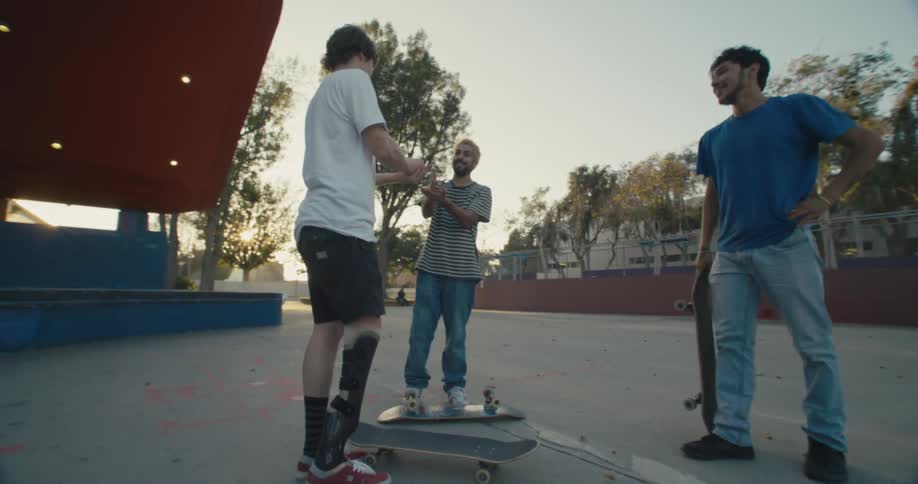 A group of skateboarders flip their skateboards and then laugh and smile