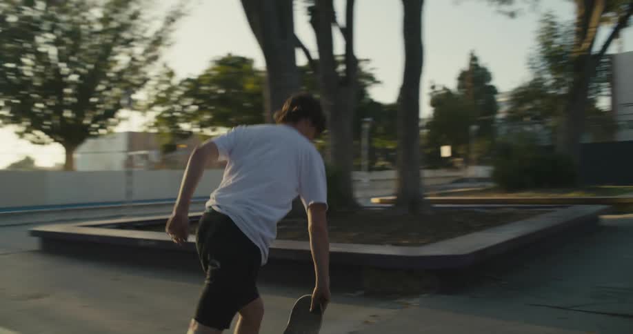 A man kicks up his skateboard and drops it back down to skate off with his friends
