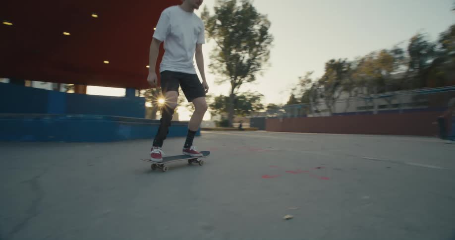 A young man does a flip on a skateboard in a skate park