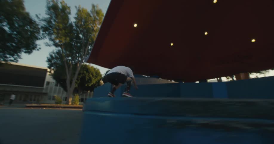 Skateboarder jumps onto platform under pavilion then jumps off