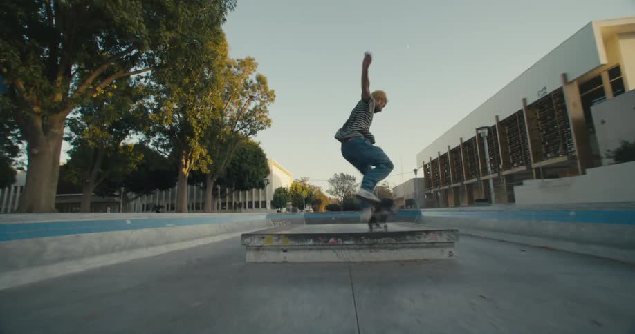 A man jumps onto a ledge on his skateboard and spins around