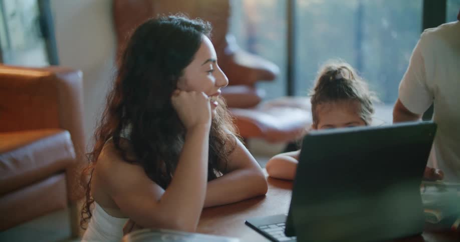 Parents chat while their daughter watches a laptop screen