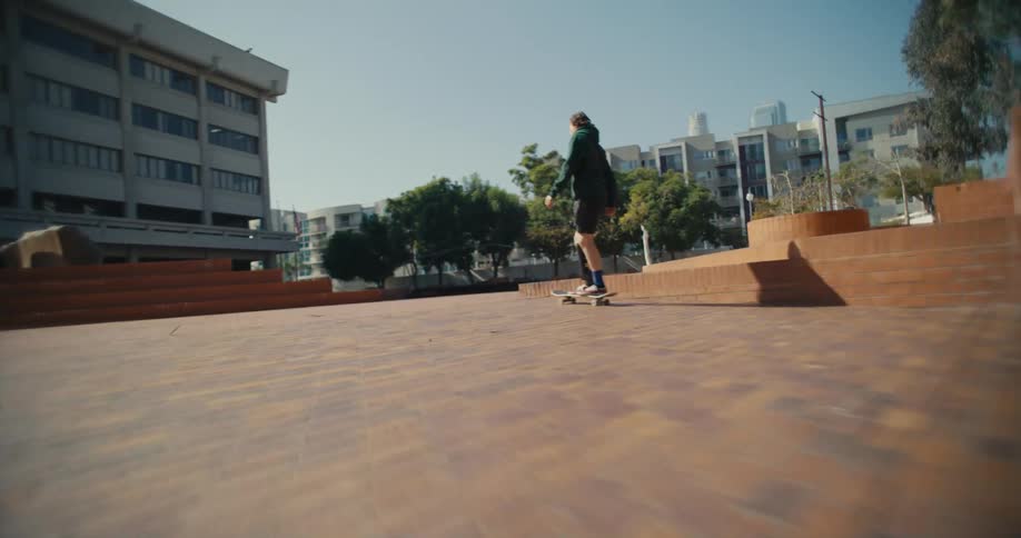 A man with a prosthetic leg skates along a brick sidewalk in the city