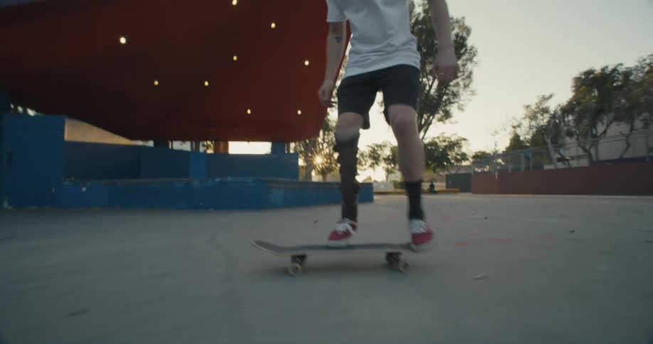 A man with a leg brace successfully jumps on his skateboard