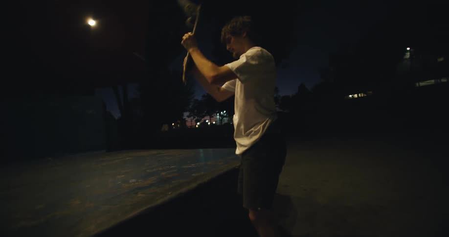 A man gets angry and smashes his skateboard on the edge of the concrete platform