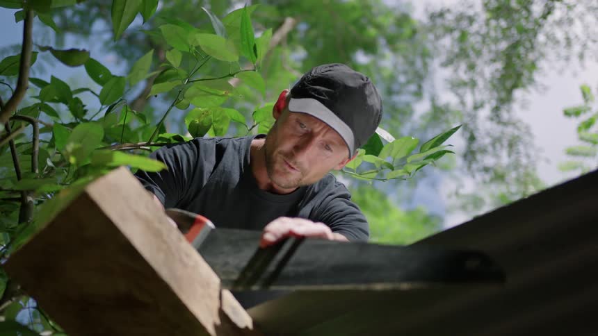 Man measures and marks wooden beam before sawing through it