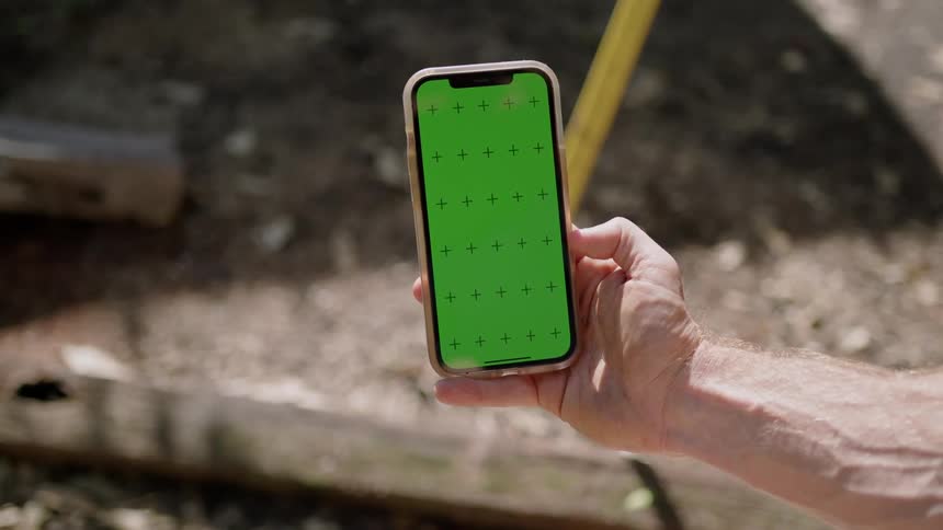 A man scrolls through his smartphone while sitting outside