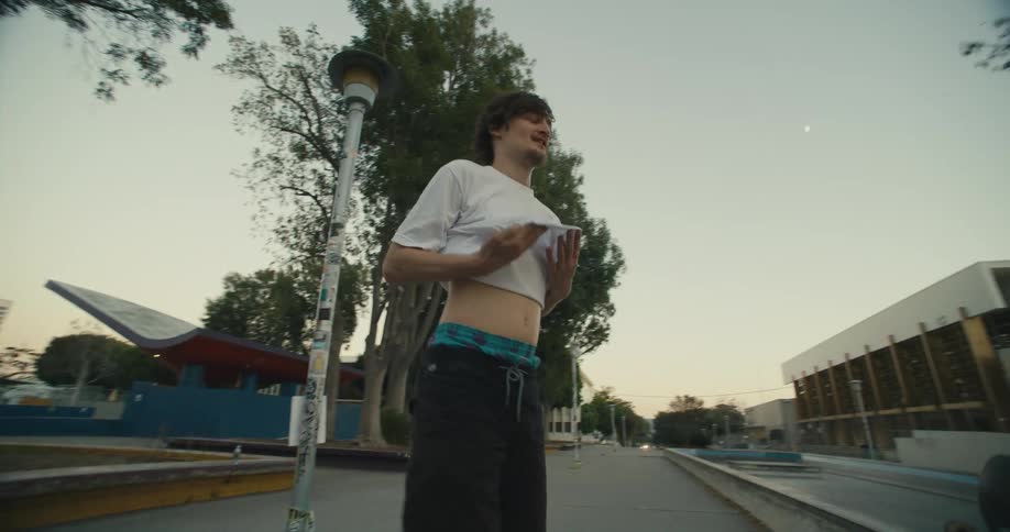 A young man skateboards toward others with skateboards in a public town area