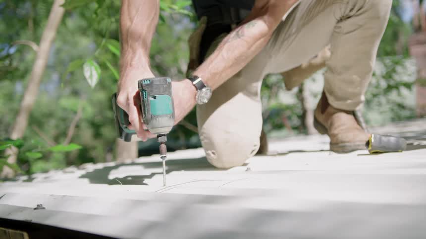 Man uses battery operated drill to add screw into metal panel