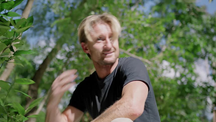 A mand drills a hole into a shed rooftop and stops to run his hand through his hair