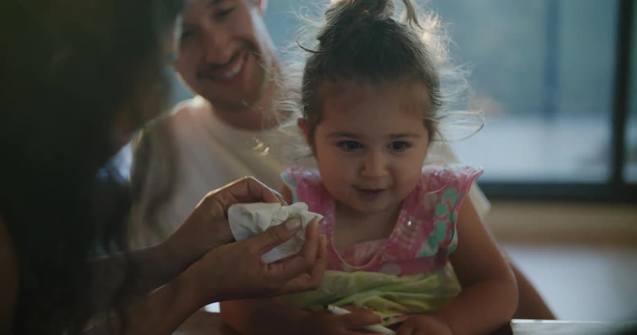 A woman uses a napkin to clean a young girls face