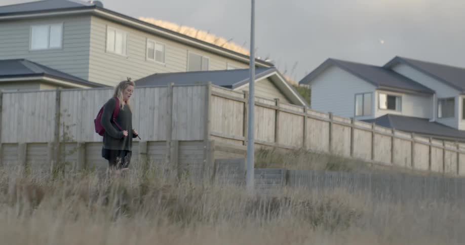 A woman is walking on the street by some homes