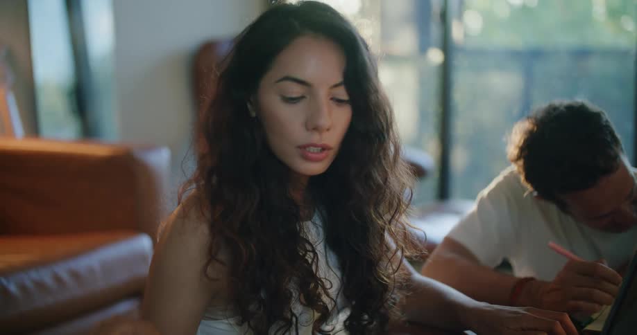 A young woman works at home as her family sits nearby