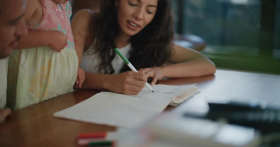 A woman draws for her daughter while sitting on the floor
