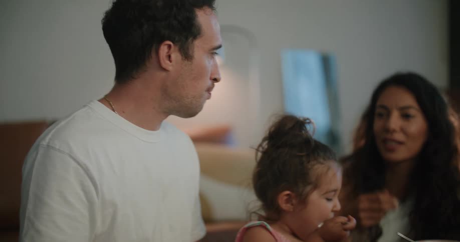A family all sit together at a kitchen table and eat from bowls
