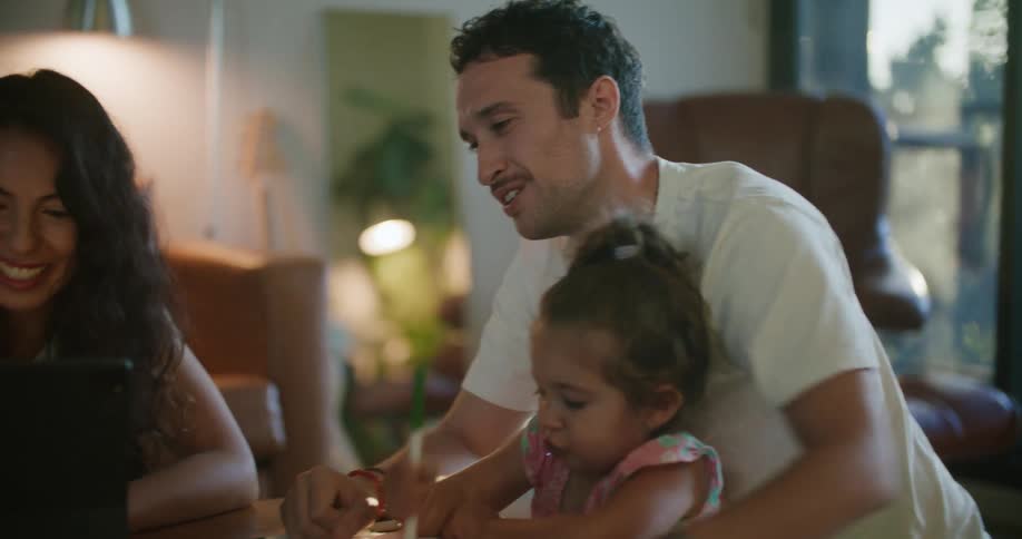 A family sits at a table with a computer smiling and talking together