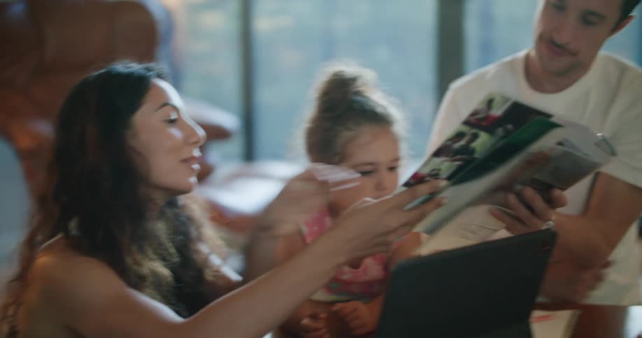 A woman looks at a magazine and passes it to her husband beside her