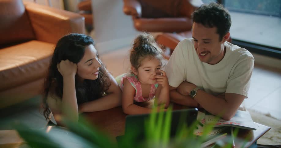 Young family watching a movie on laptop in living room with toddler