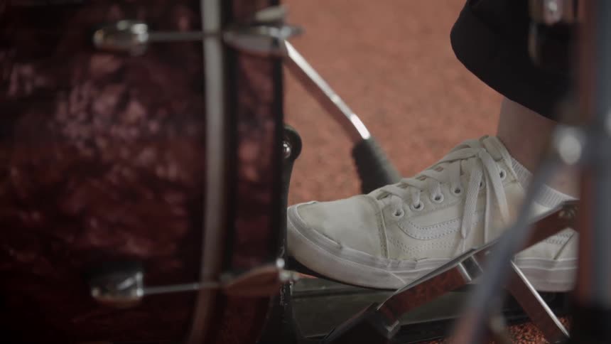 A foot is pushing the pedal of a drum set