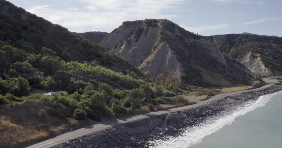 The waves crash against the shore of this hill covered area