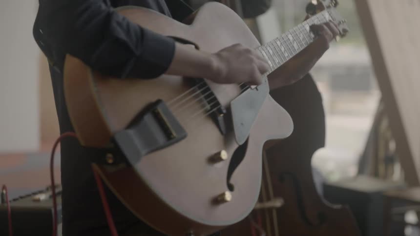 Close up of someone playing a guitar with a band