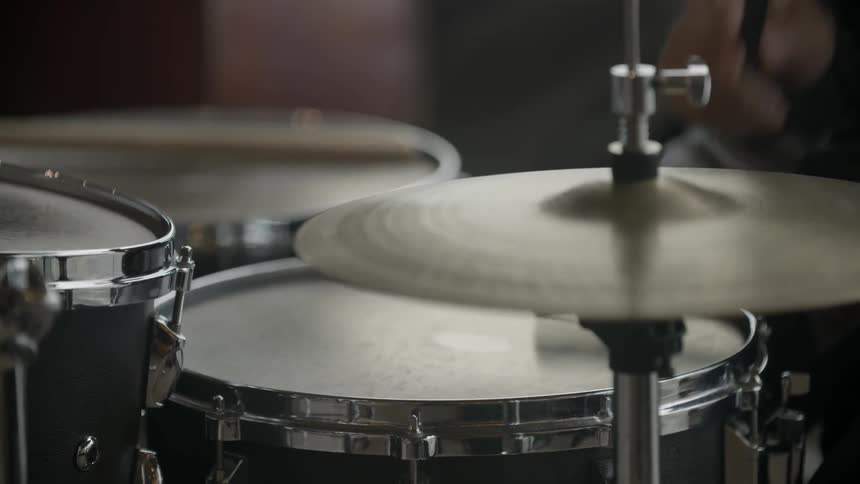 A drummer taps a snare and symbol