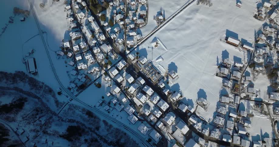 An aerial view of snowy houses in a neighborhood on a winter day