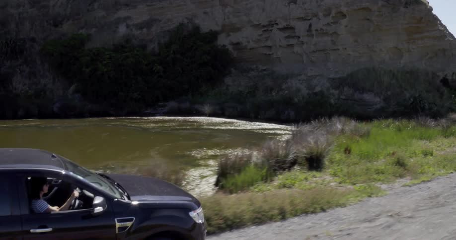 A truck is driving off road near a mountain