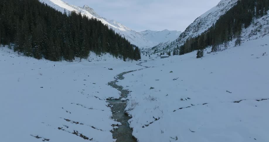 Aerial view of a small river streaming down a valley between the mountains at morning
