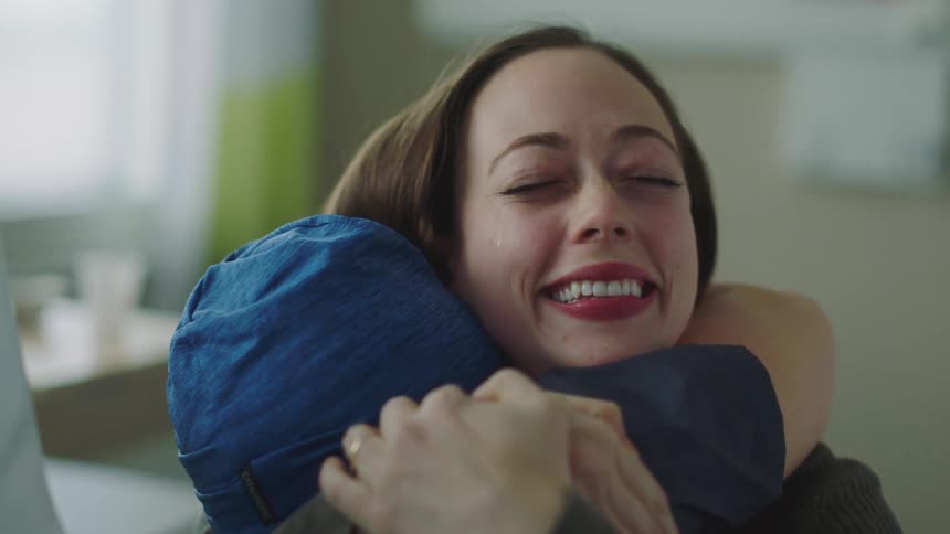A man and woman embrace and smile in a hospital room