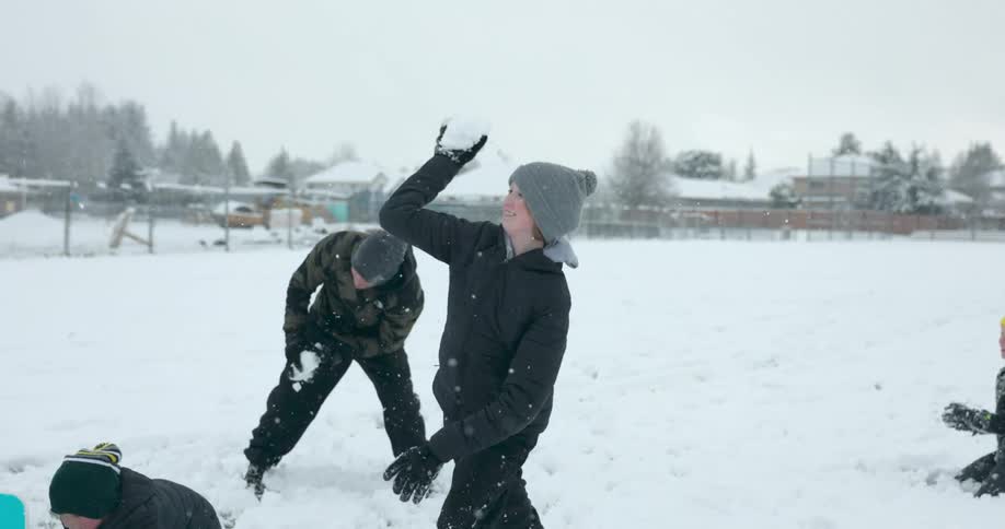 Children have a snowball fight as it snows