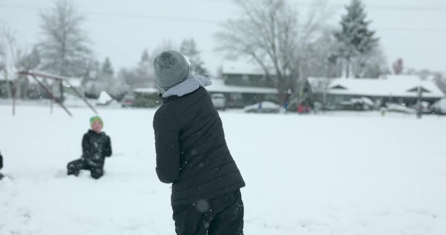 Three boys have a snowball fight in a neighborhood
