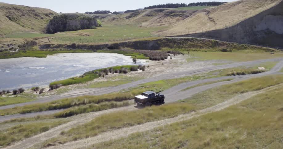 A car is driving down small dirt roads by a range