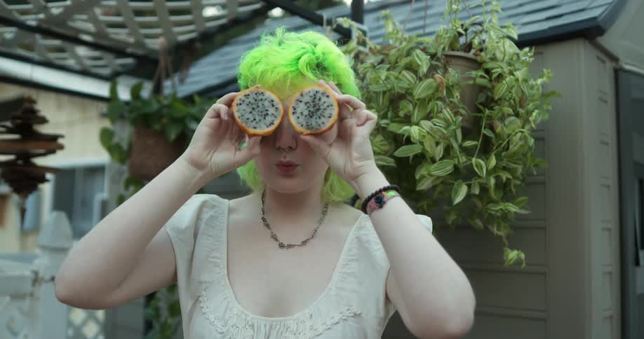 A woman lifts dragon fruit over her eyes