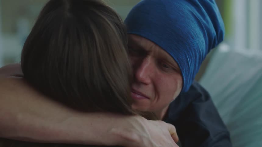 Hospital patient lying in bed cries and hugs woman