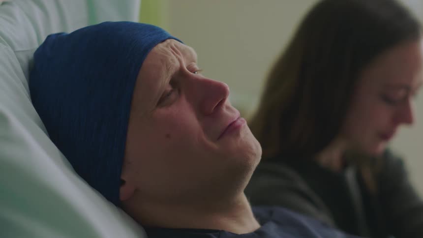 Patient lying in bed and visitor both cry then she turns to comfort him