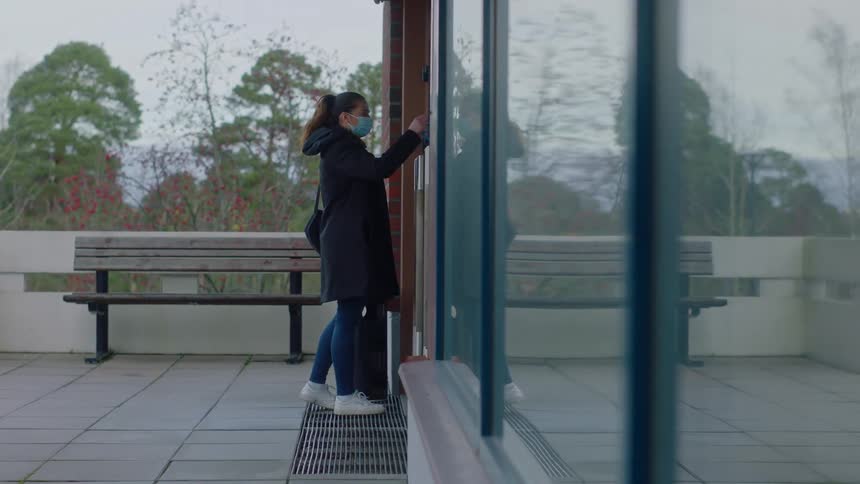 A woman scans a badge and opens the door to an office building