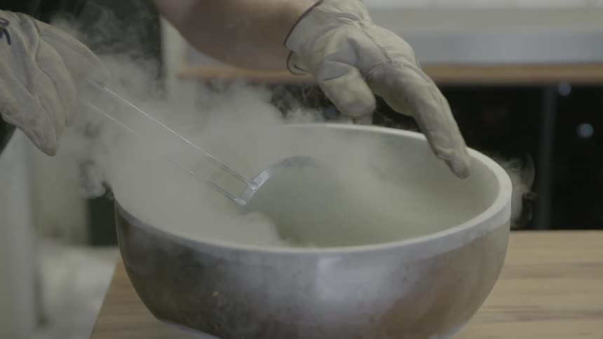 Something frozen is being mixed in a metal bowl