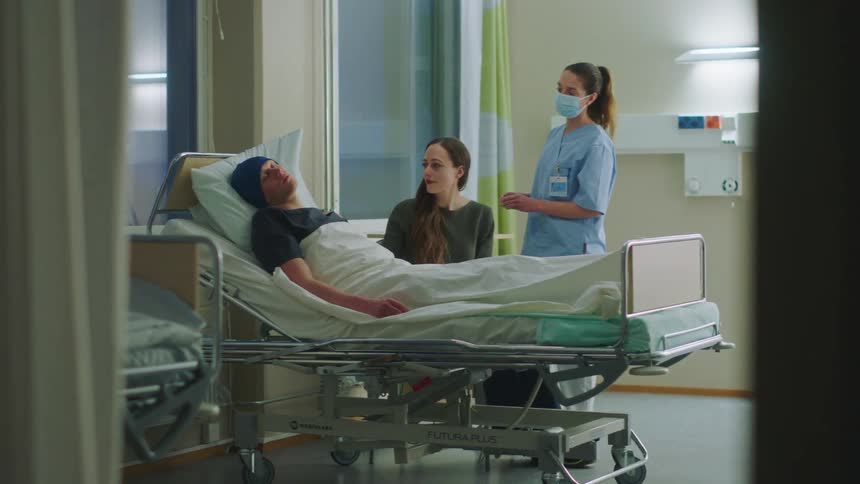 A nurse wakes a patients wife so that she can hand him his medicine