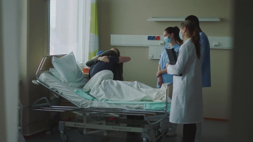 A man hugs his wife after receiving good news from the medical team in his hospital room