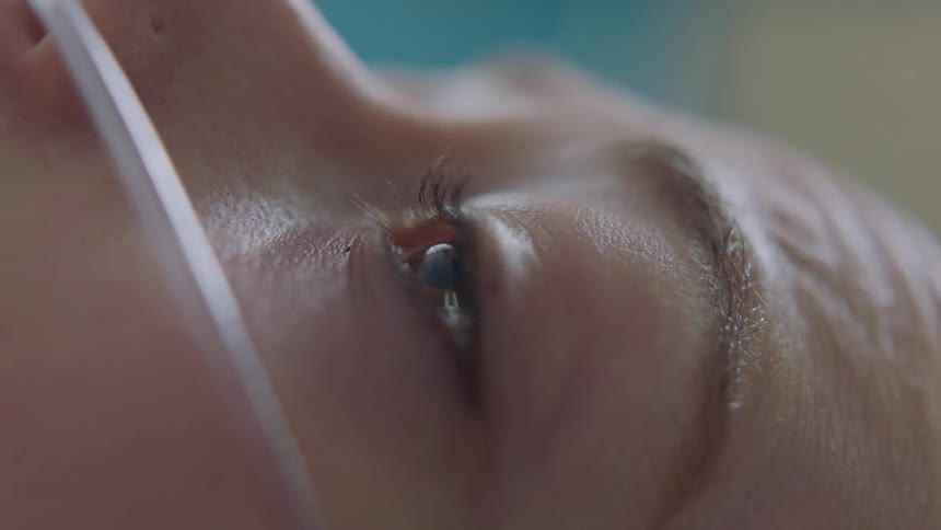 Extreme close up of the wet teary eye of a patient wearing a nasal cannula in the hospital